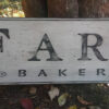 Farmhouse Bakery wood Sign laying against a tree.