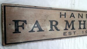 Closeup of the Hanna Farmhouse sign in rustic nutmeg paint.
