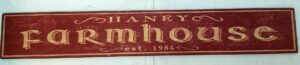The Haney Farmhouse wood sign, Irish themed and rustic red background with gold lettering.