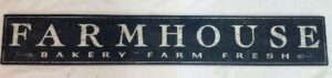 A rustic distressed black farmhouse sign with off white lettering.