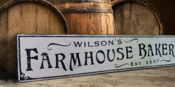 The Farmhouse Bakery Sign with a custom name, sign against barrel backdrop