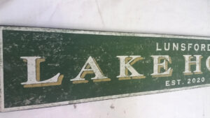 Close-up of Lunsford Lake House Sign with forest green background