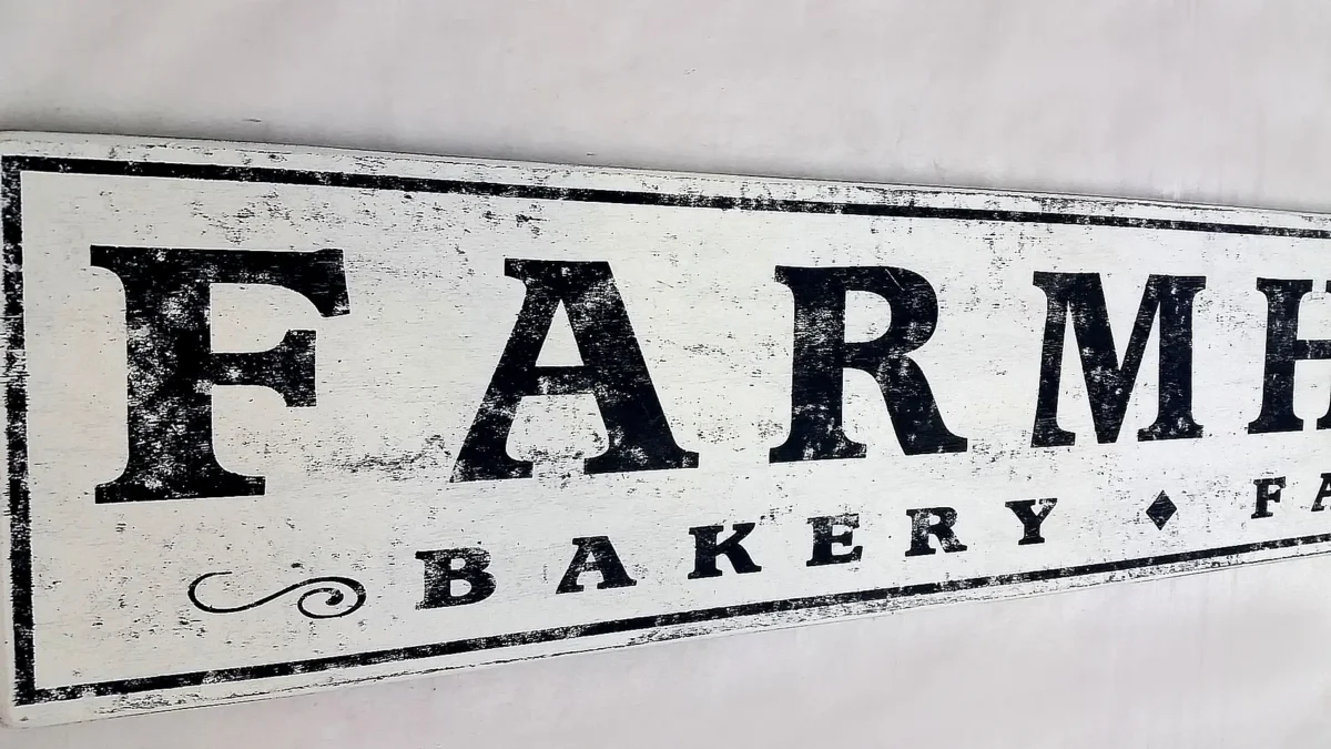 Detailed view of antique farmhouse sign showcasing distressed finish and lettering