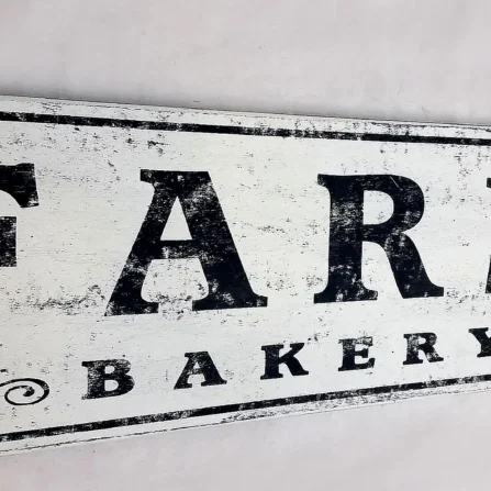 Detailed view of antique farmhouse sign showcasing distressed finish and lettering