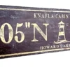 Closeup of antique wood sign with lighthouse and personalized coordinates