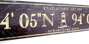 Closeup of antique wood sign with lighthouse and personalized coordinates