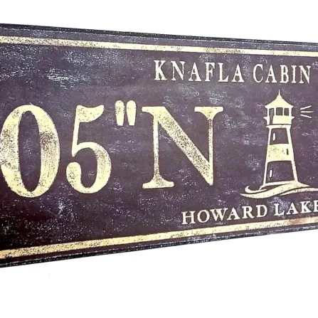 Closeup of antique wood sign with lighthouse and personalized coordinates