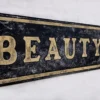 Closeup view of gold letters on a black distressed beauty parlour sign