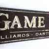 Closeup view of "Game Room" sign showcasing gold letters and game details