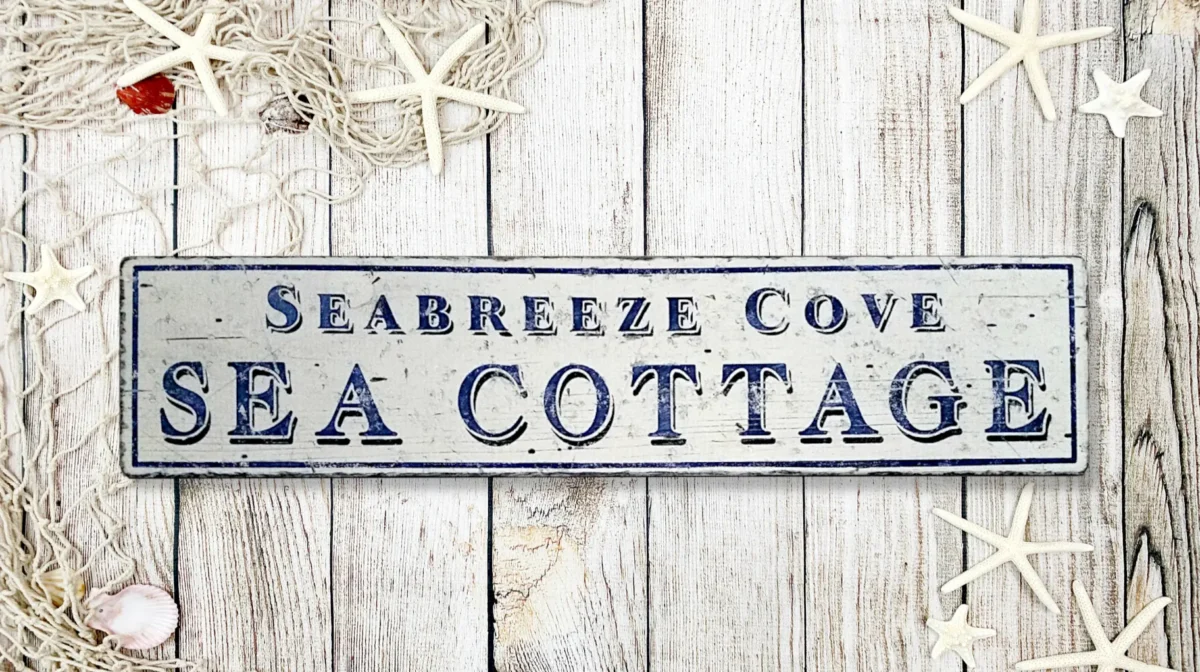 Antique-style Sea Cottage sign with distressed white background and navy blue letters