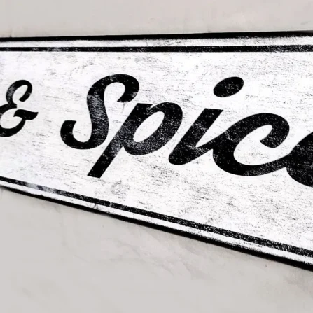 Closeup view of the vintage style sign showcasing elegant black cursive lettering on a crisp white background.