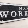Closeup view of the antique workshop sign showcasing intricate decorative elements and crisp white letters.