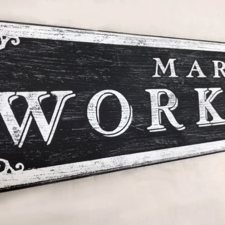 Closeup view of the antique workshop sign showcasing intricate decorative elements and crisp white letters.
